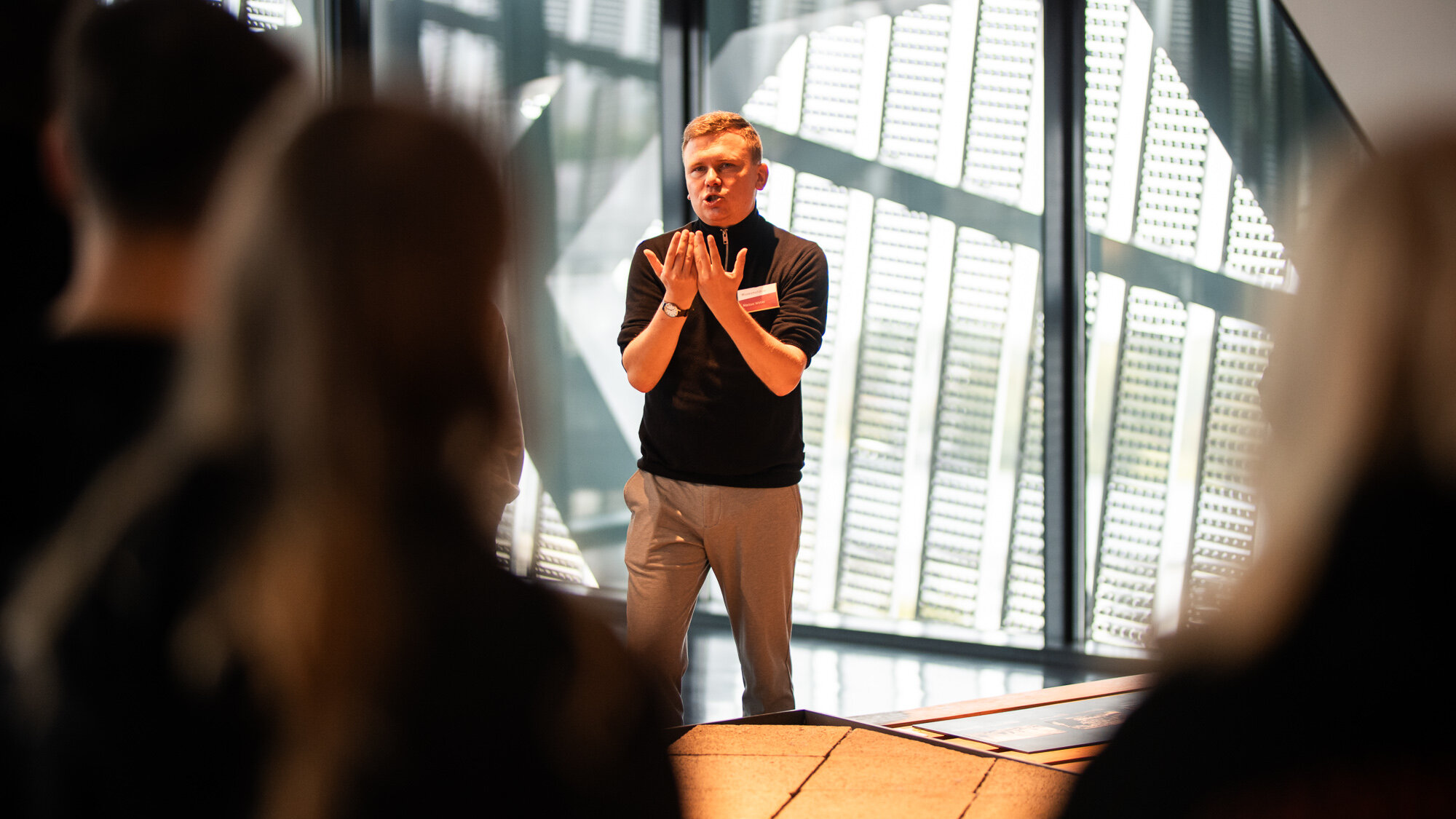 Ein männlicher Museumsguide spricht mit Besucherinnen und Besuchern in der Spitze des Museumsneubaus von Daniel Libeskind.  