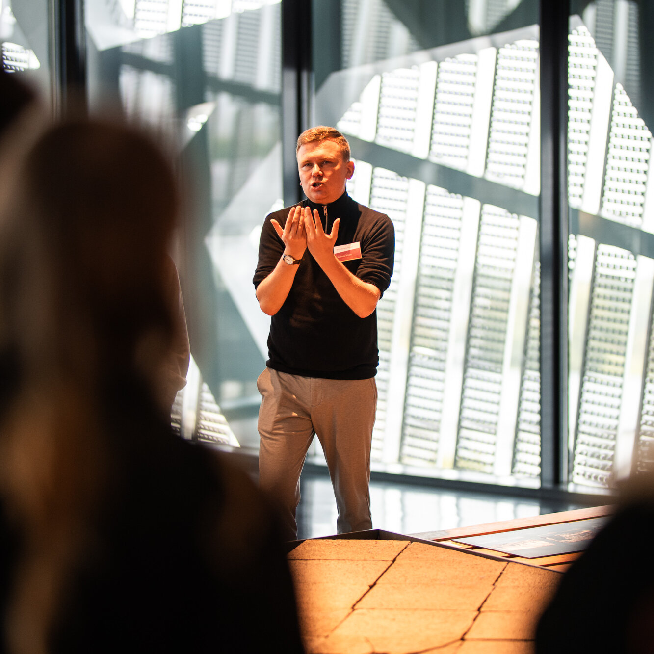 Ein männlicher Museumsguide spricht mit Besucherinnen und Besuchern in der Spitze des Museumsneubaus von Daniel Libeskind.  