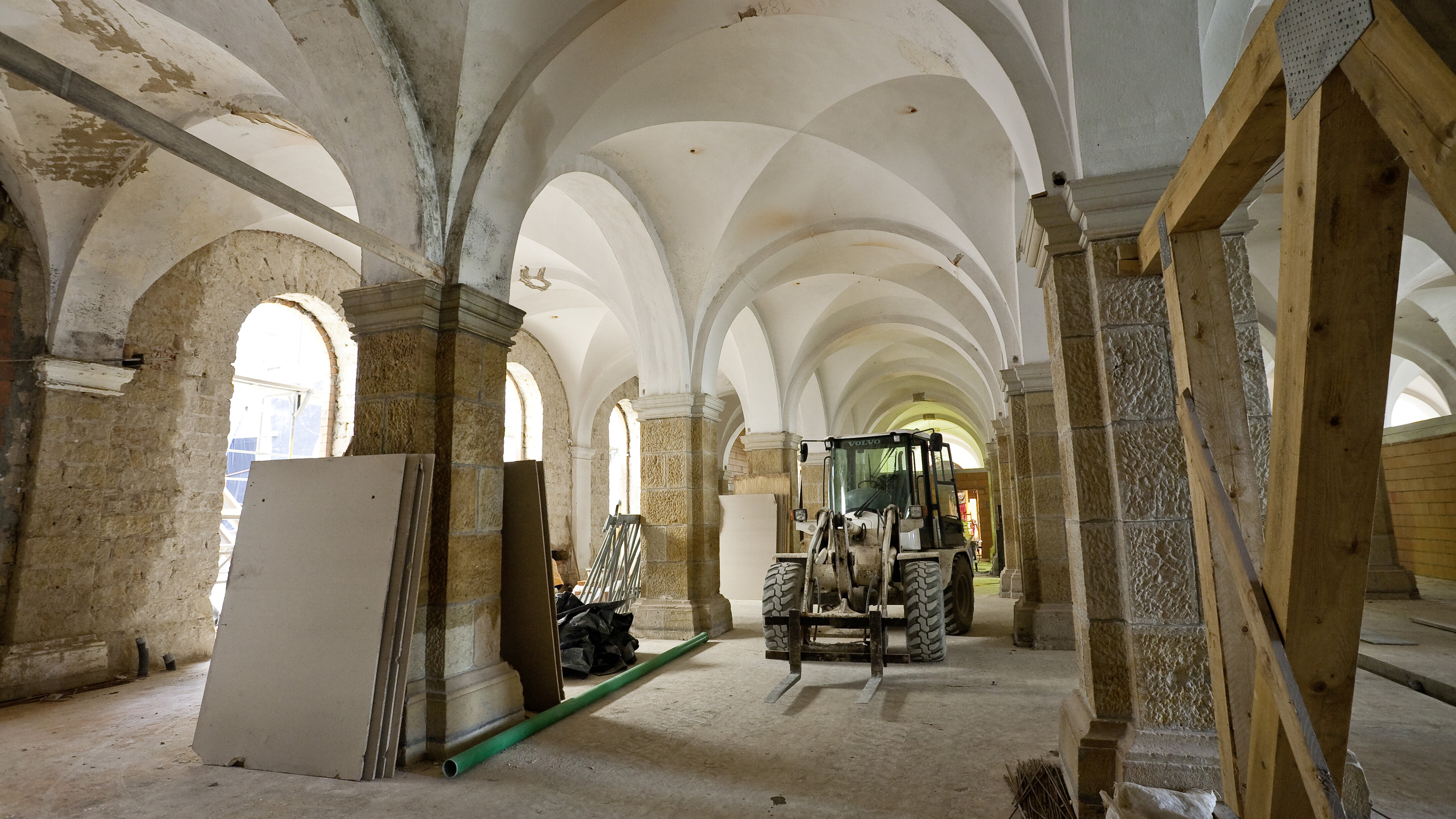 Das Bild zeigt ein Baufahrzeug zwischen Säulen des Museumsaltbaus. 