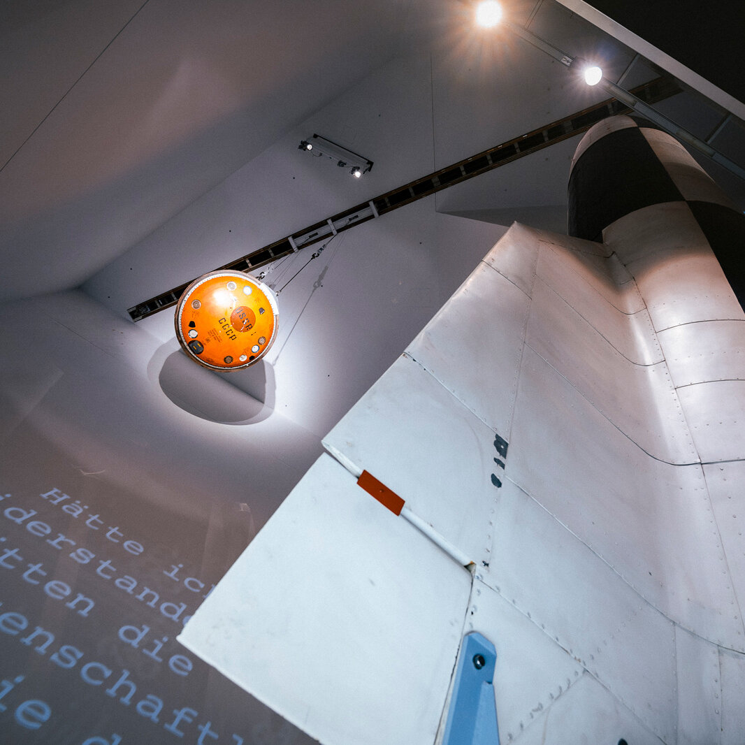 Auf der Aufnahme sind eine Raumfahrtkapsel und eine V2-Rakete zu sehen. 