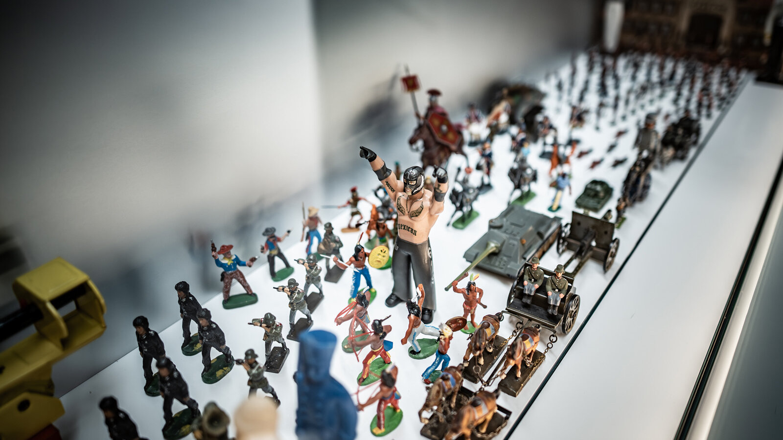 Das Bild zeigt eine Parade an Spielzeugen, die Gewalt und Krieg thematisieren. 