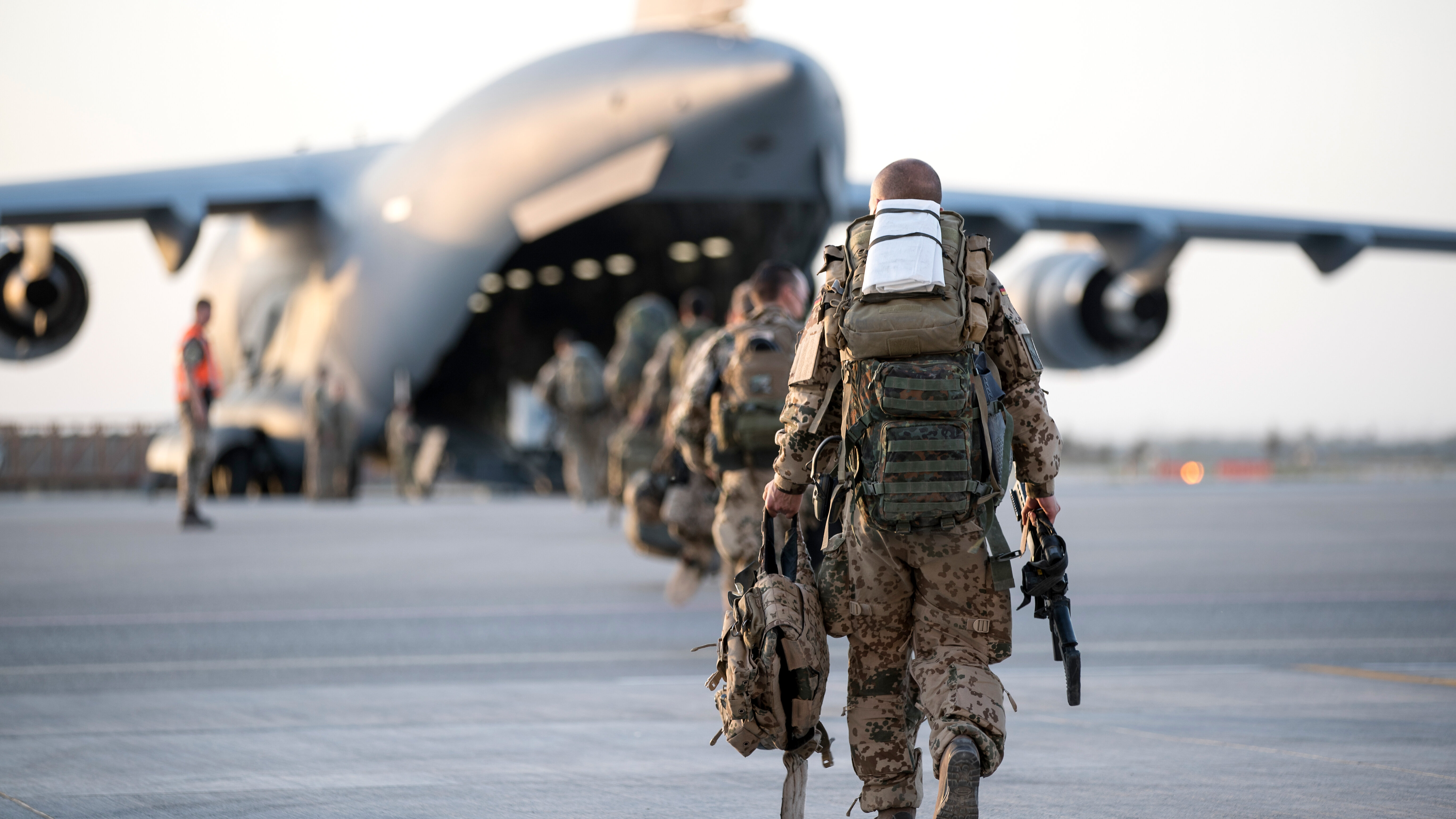 Das Bild zeigt Soldaten, die zu einem Transportflugzeug laufen.