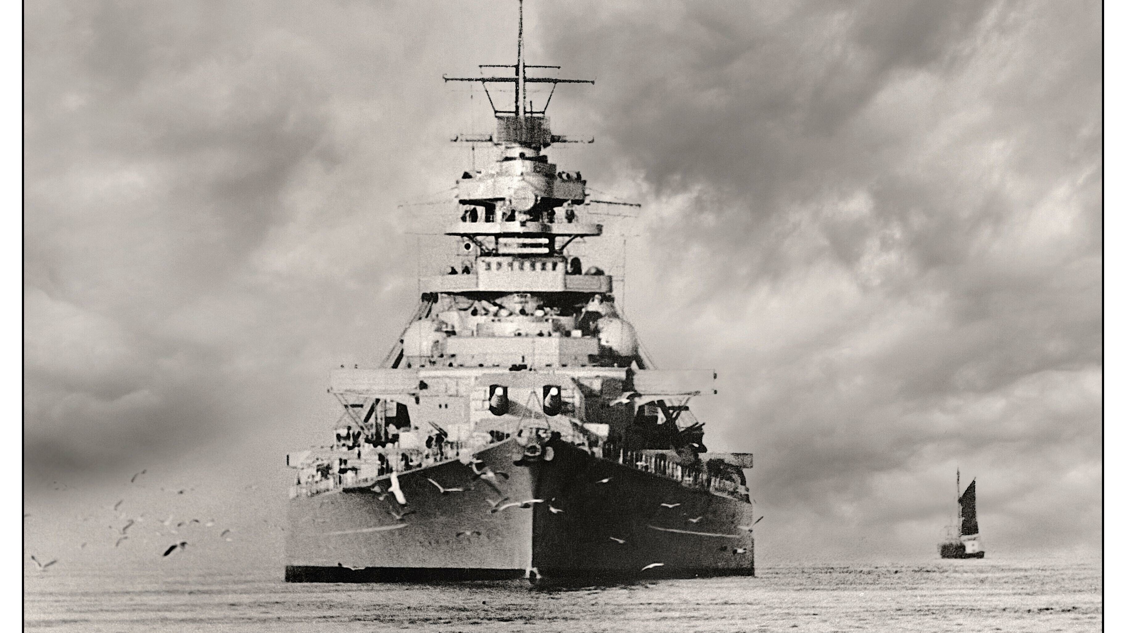 Das schwarz-weiß-Foto zeigt das riesige Schlachtschiff Bismarck von vorn im Meer fahrend. 
